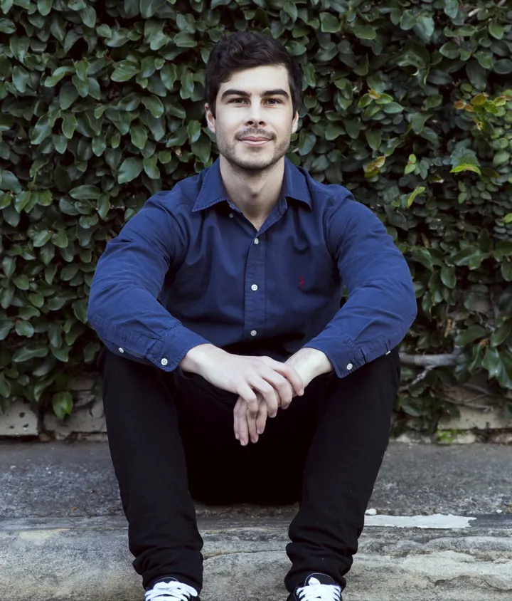 Luke Smith sitting on a step in front of an ivy wall in Sydney